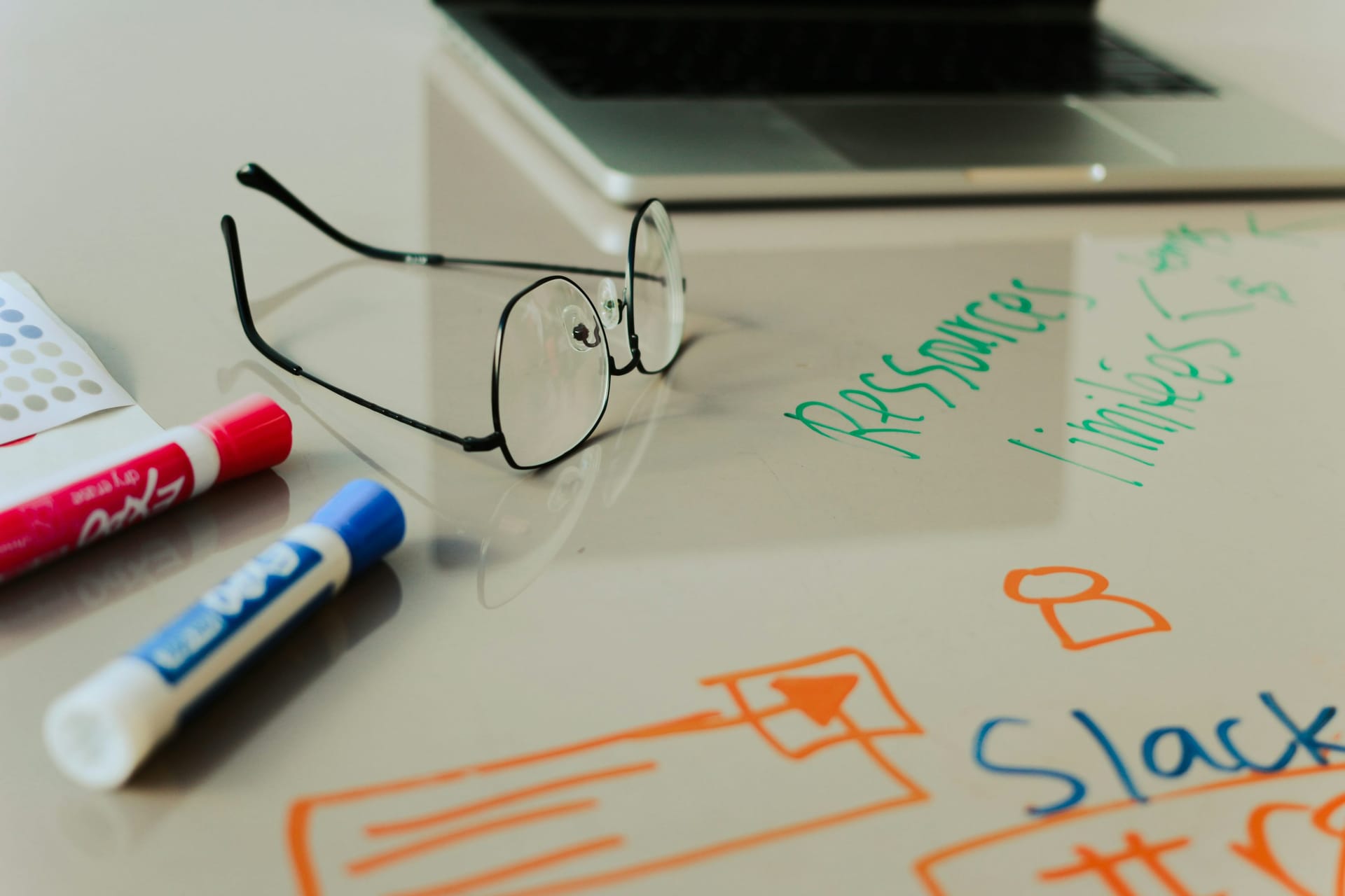 Whiteboard with marketing strategy notes, markers, and reading glasses representing digital marketing agency planning work
