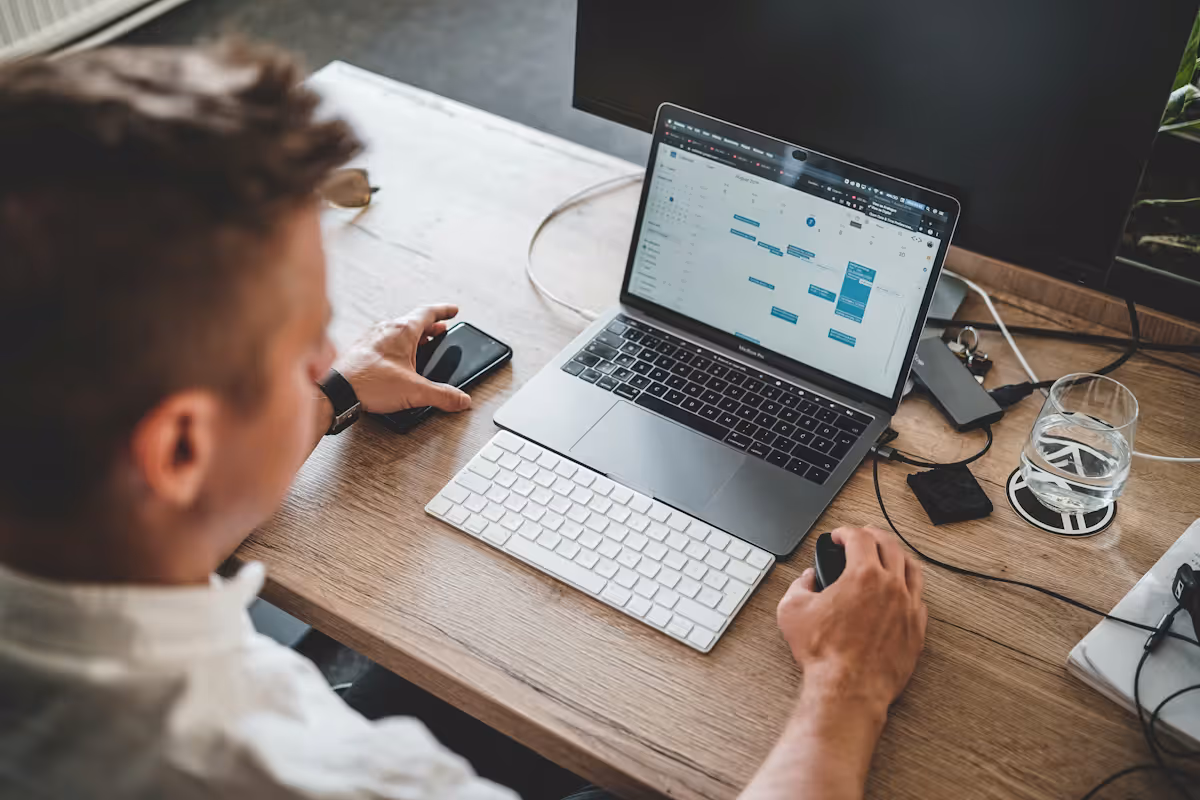 Business owner working at desk with laptop, external keyboard, mouse and monitor reviewing Google Ads data