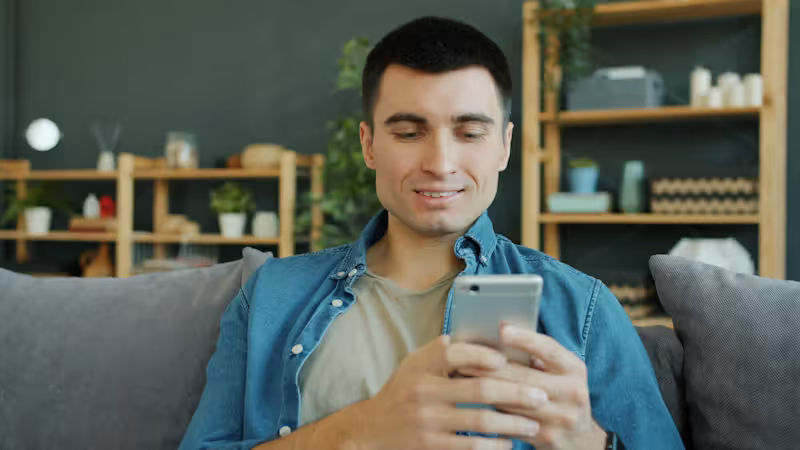 Person browsing a website on smartphone while seated on a couch, mobile-first website design